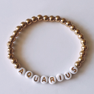 Gold and white beaded bracelet with the word "AQUARIUS" spelled out.