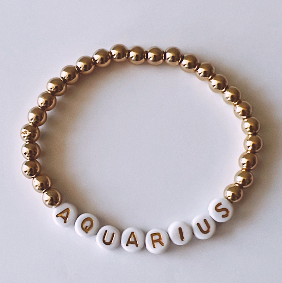 Gold and white beaded bracelet with the word "AQUARIUS" spelled out.