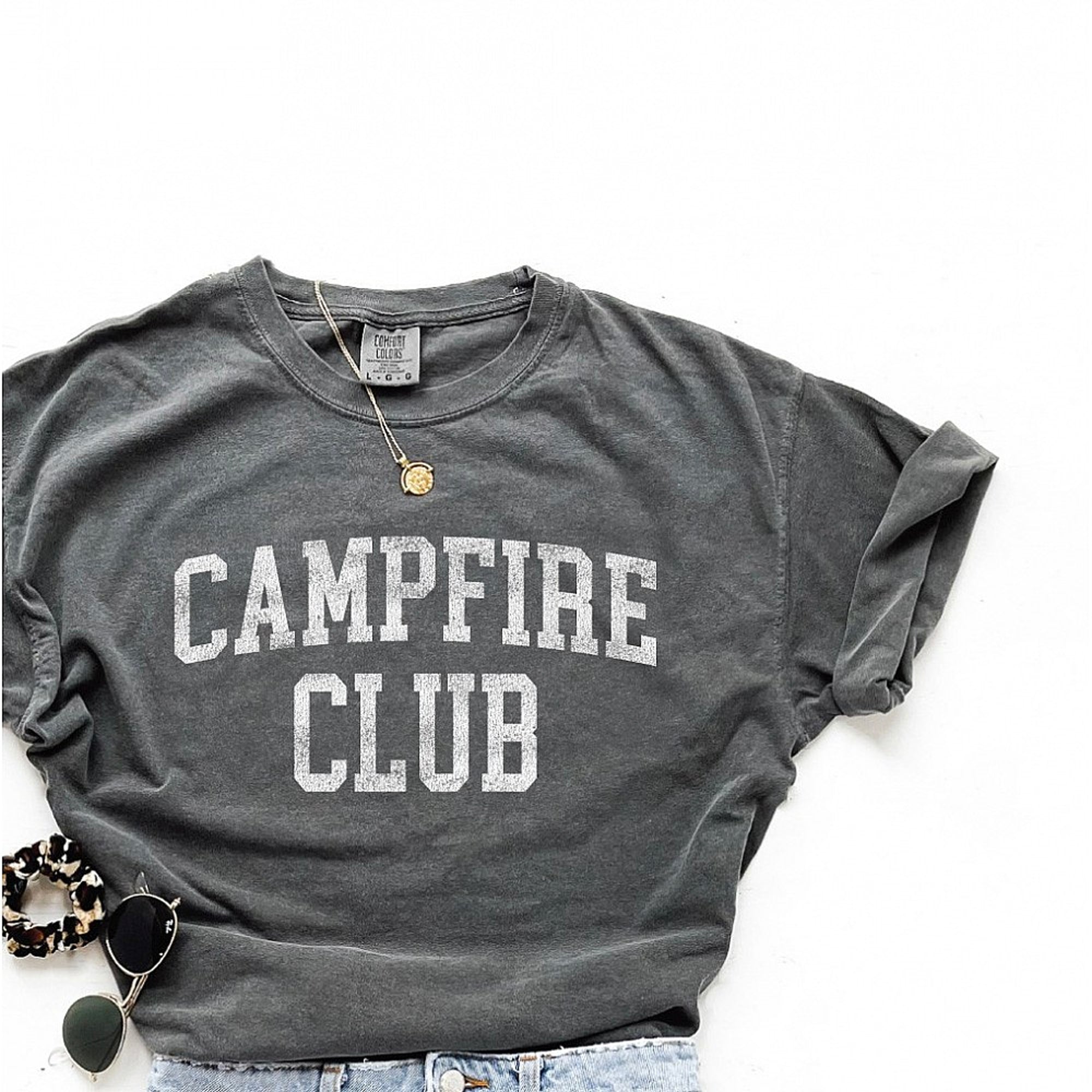Gray t-shirt with "CAMPFIRE CLUB" printed in bold white letters, styled with accessories.