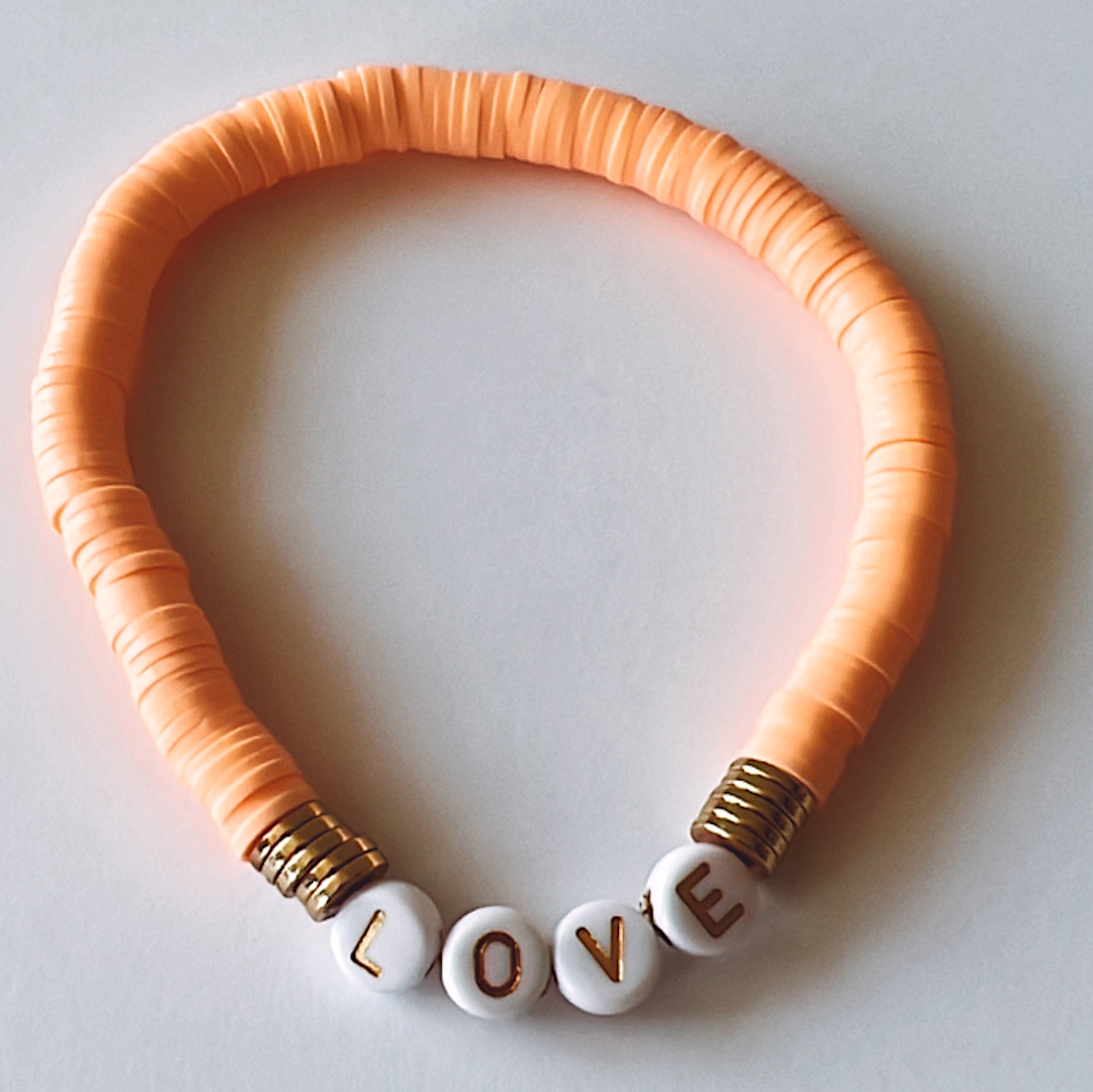 Orange beaded necklace with the word "LOVE" spelled out in white beads.