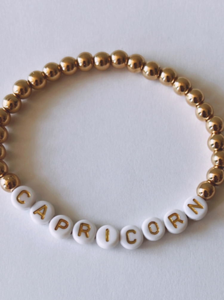 Gold and white bead bracelet with the word "CAPRICORN" spelled out.