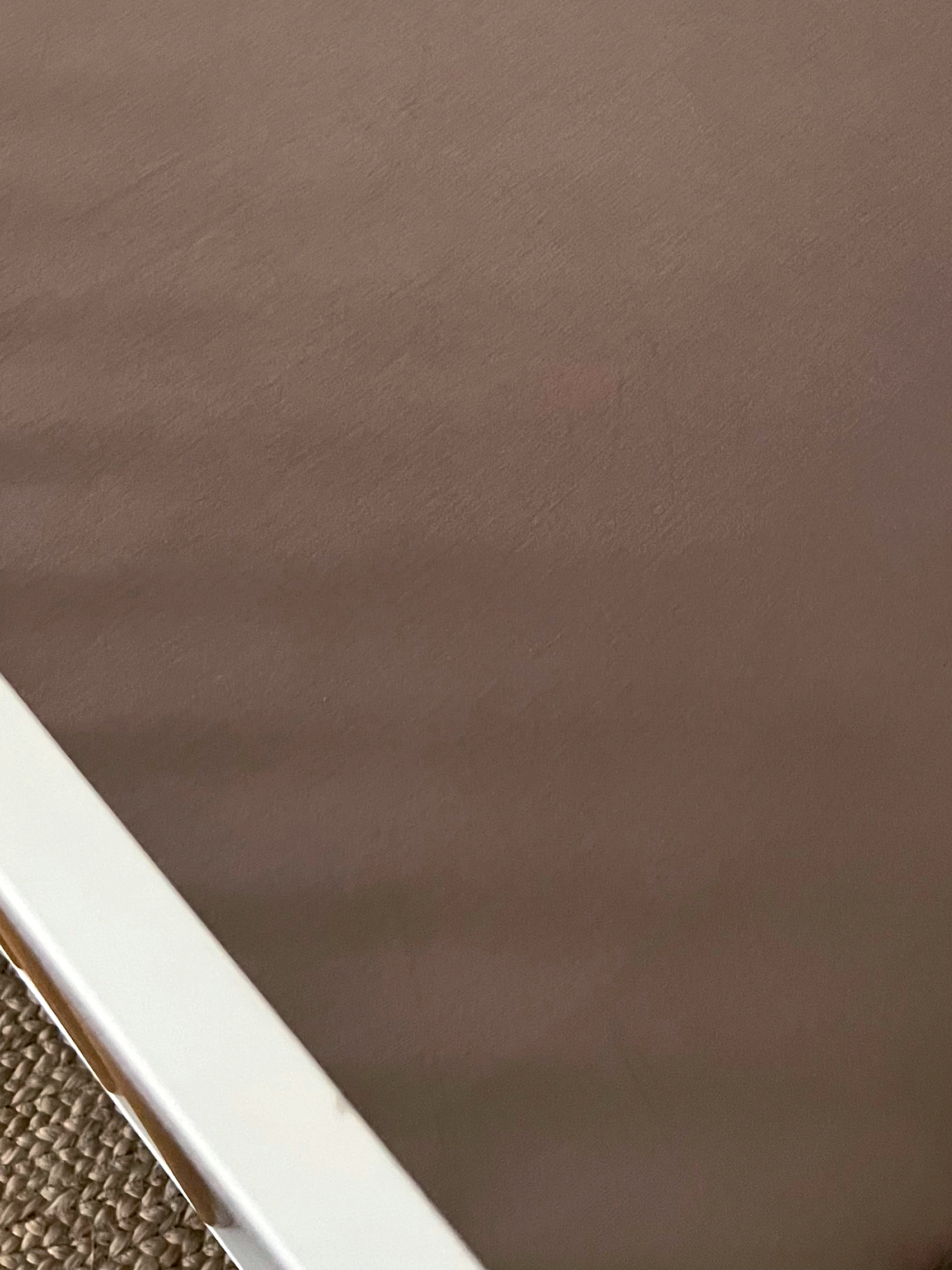 Close-up of a brown mattress edge with a white frame on a textured surface.