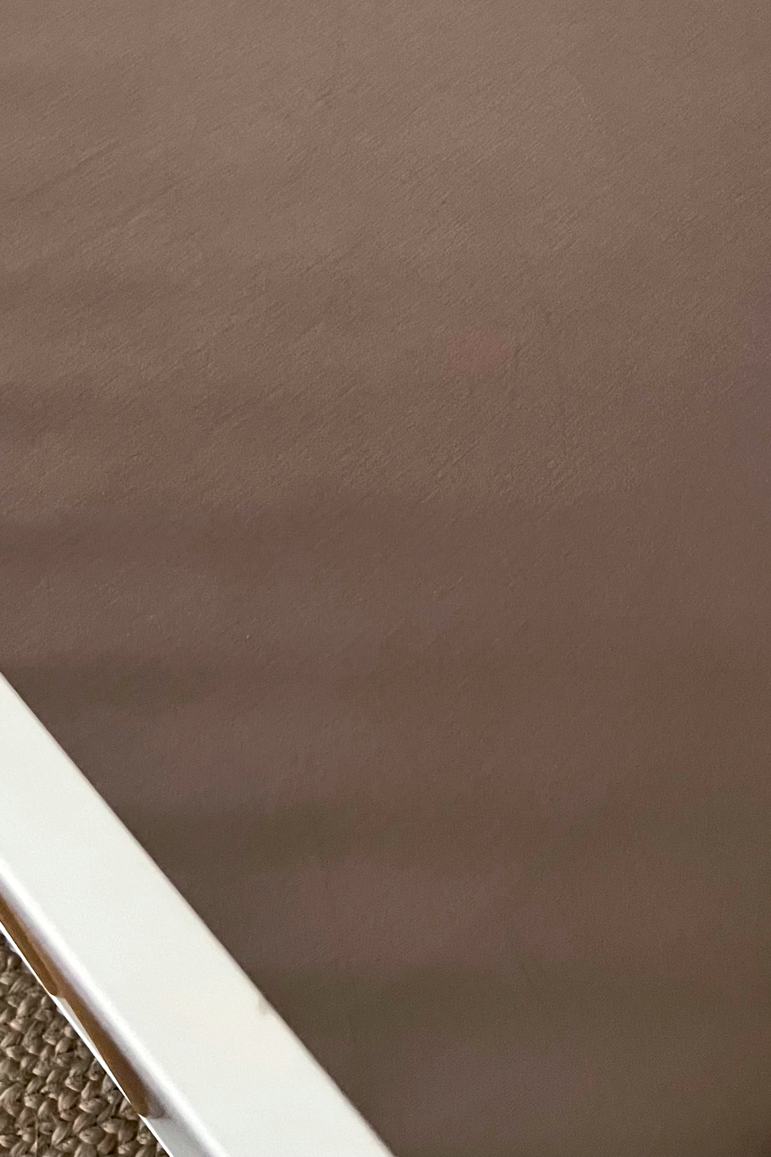 Close-up of a brown mattress edge with a white frame on a textured surface.