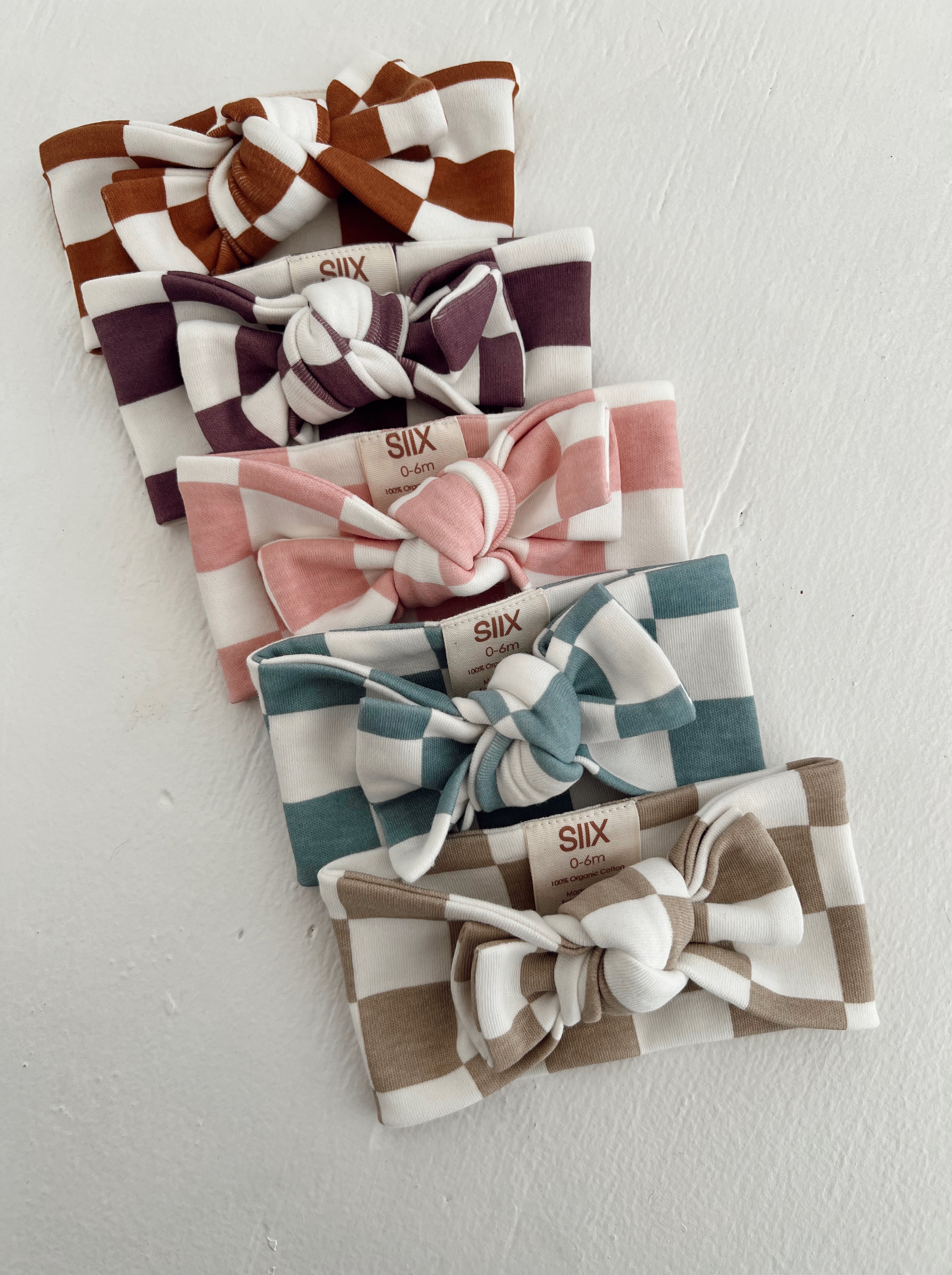 A collection of six colorful checkered baby headbands arranged in a row on a white background.