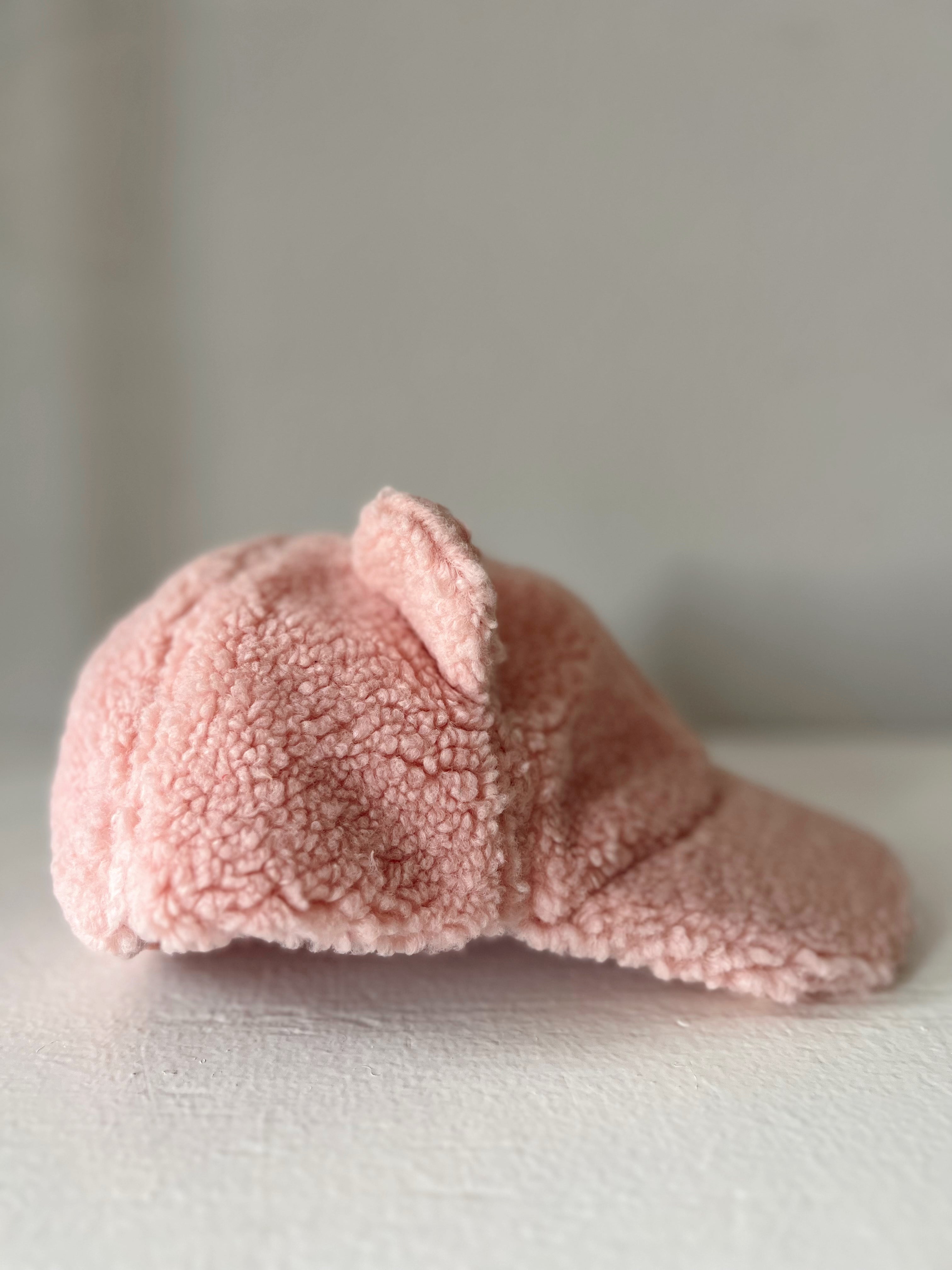 Pink plush cap with a cozy texture, displayed at an angle against a light background.