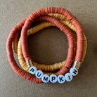 Colorful beaded bracelets in orange and yellow, featuring the word "PUMPKIN" spelled out in letter beads.
