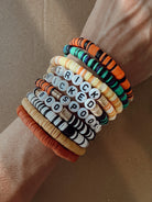 Colorful Halloween-themed bracelets stacked on a wrist, featuring words like "TRICK," "WICKED," "BOO," and "SPOOK."