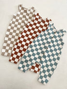 Three checkered baby rompers in beige, brown, and teal, displayed on a light background.
