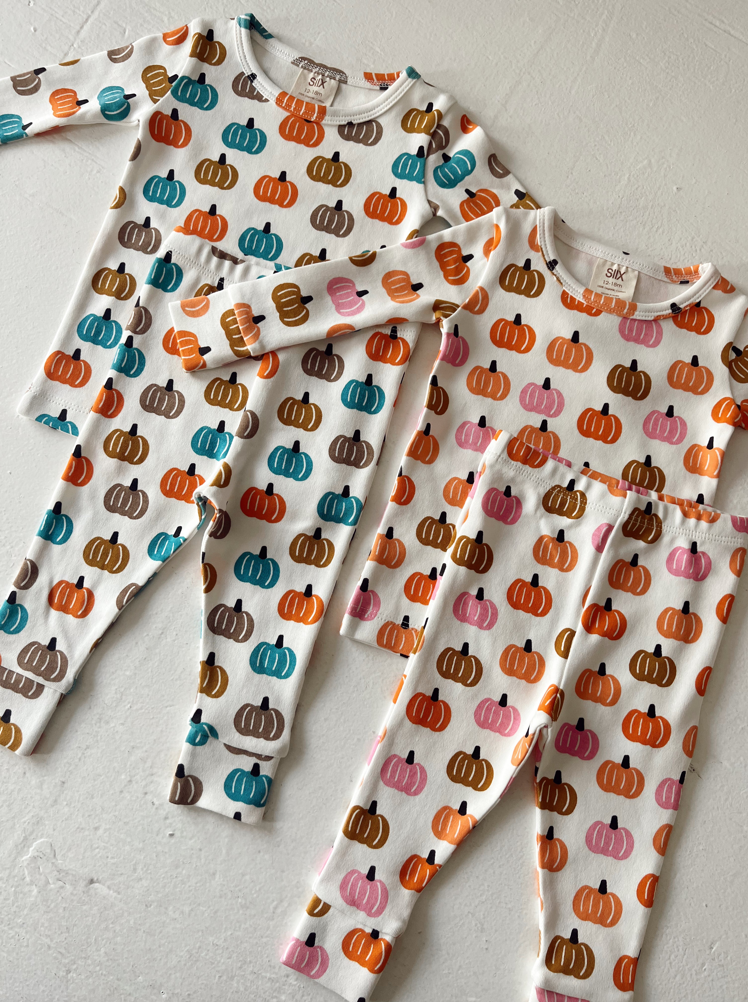 Three pairs of kids' pajamas in pumpkin pattern: colorful pumpkins on a white background, featuring various sizes.