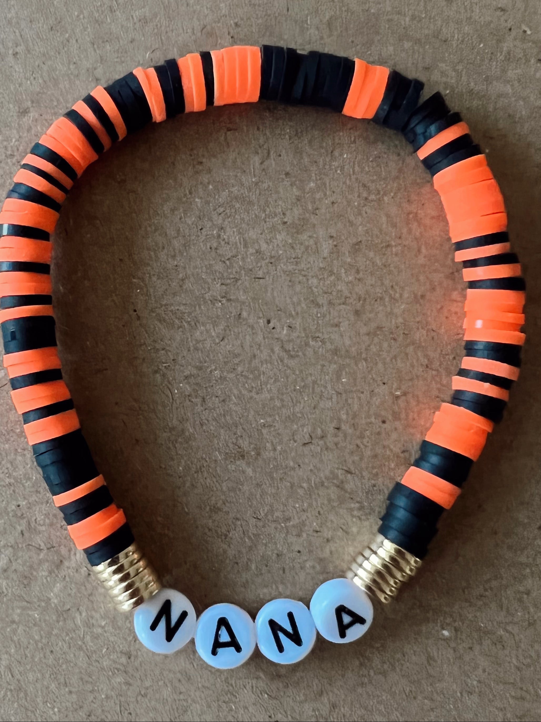 Colorful beaded bracelet with orange and black segments, featuring the word "NANA" in white beads.