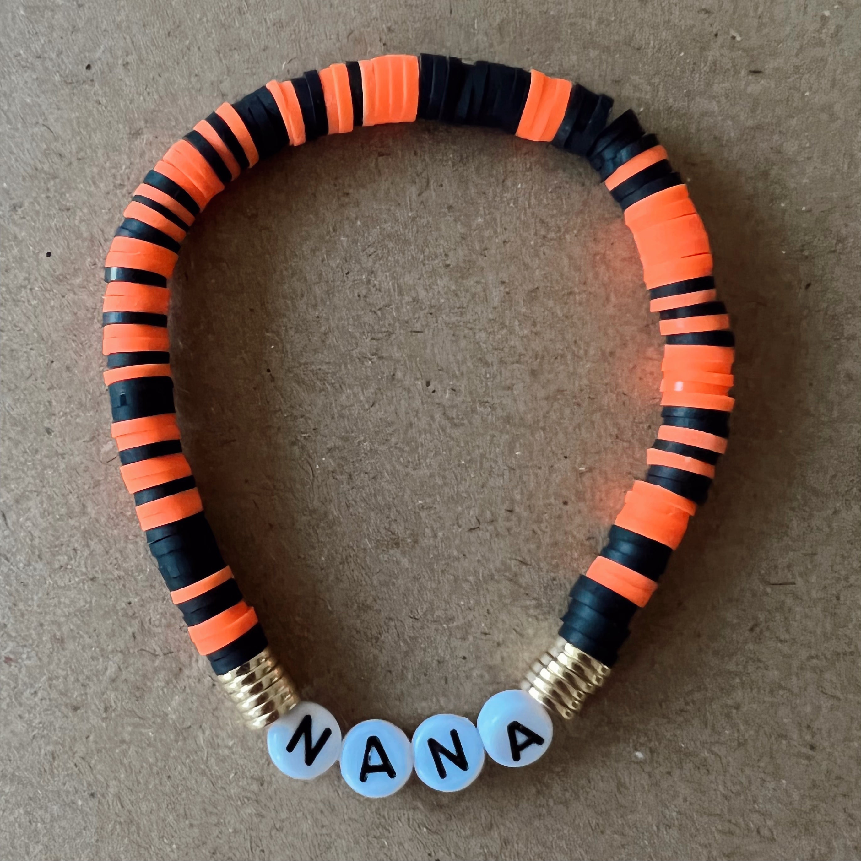Colorful beaded bracelet with orange and black segments, featuring the word "NANA" in white beads.