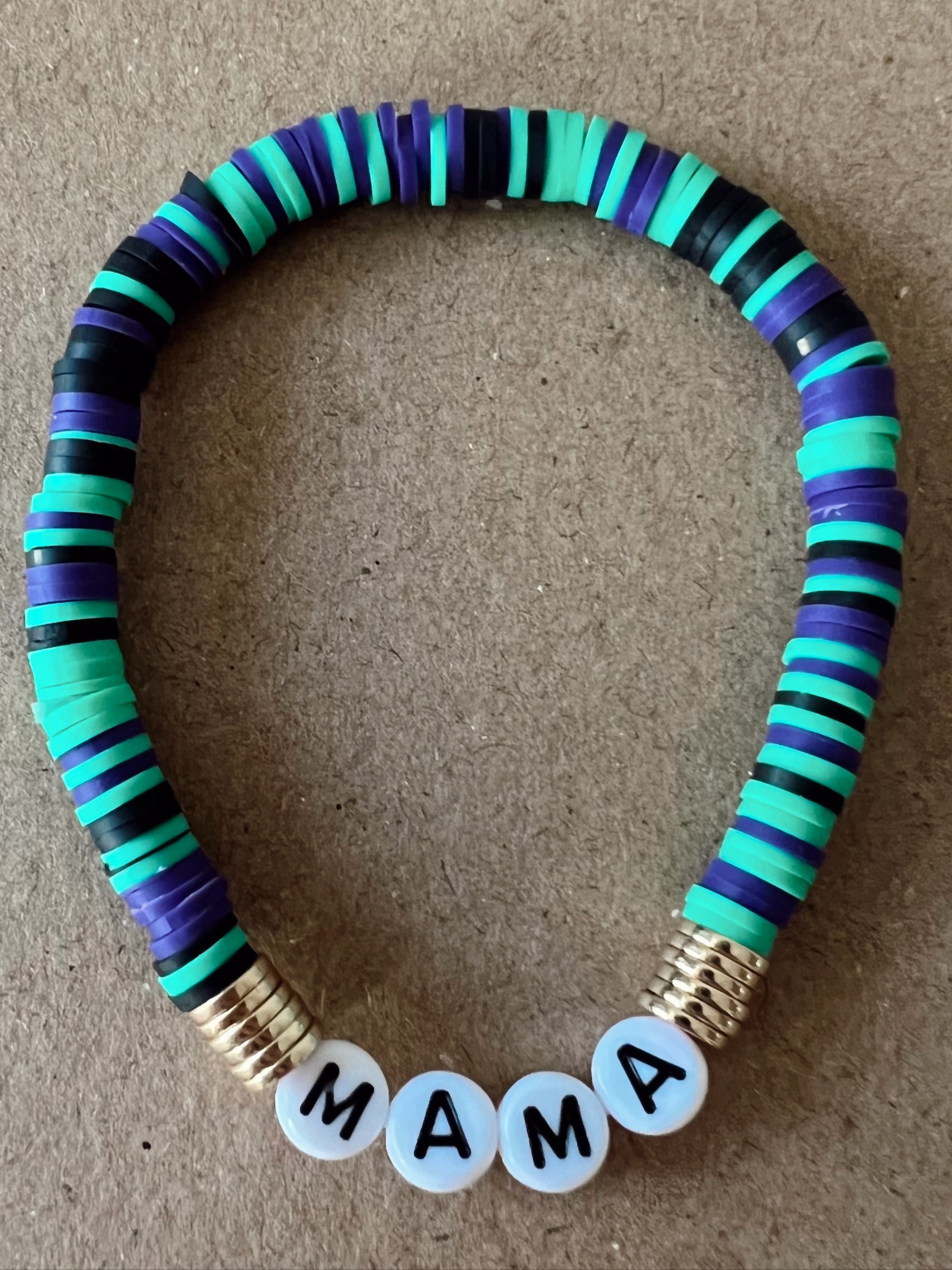 Colorful beaded bracelet with letters spelling "MAMA" on a brown background.
