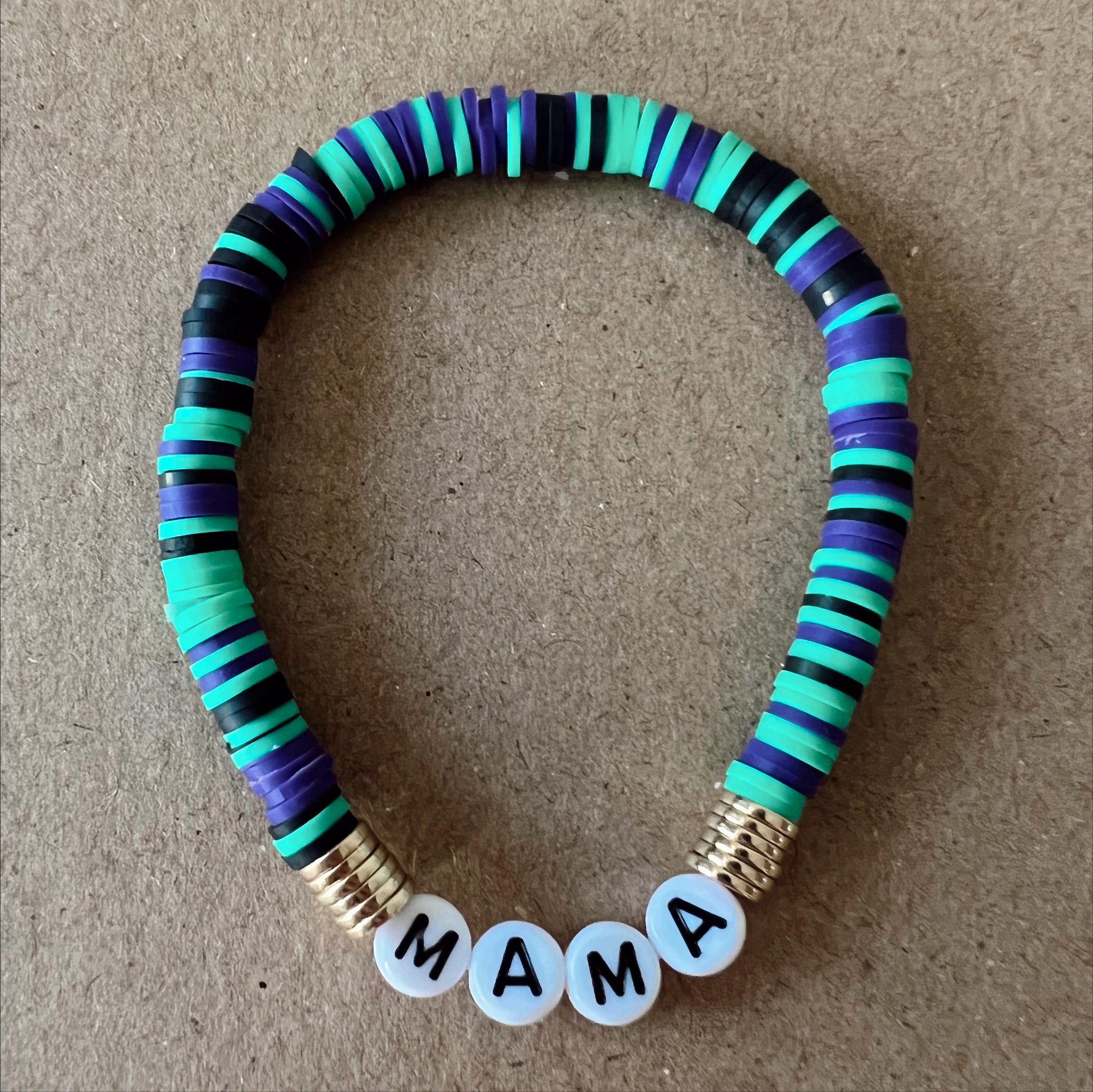 Colorful beaded bracelet with letters spelling "MAMA" on a brown background.