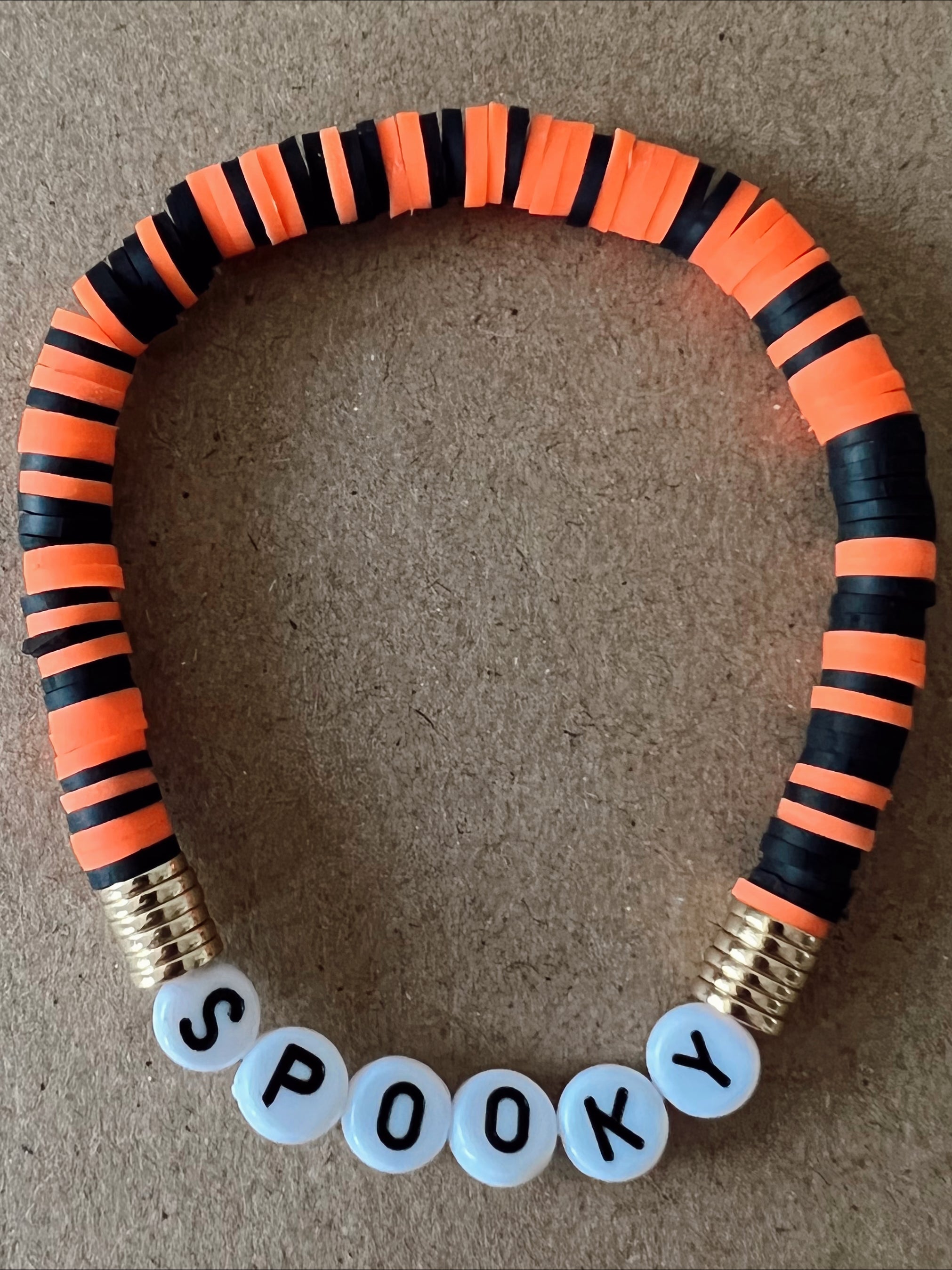 Halloween-themed bracelet with black and orange bands, featuring the word "SPOOKY" in white beads.
