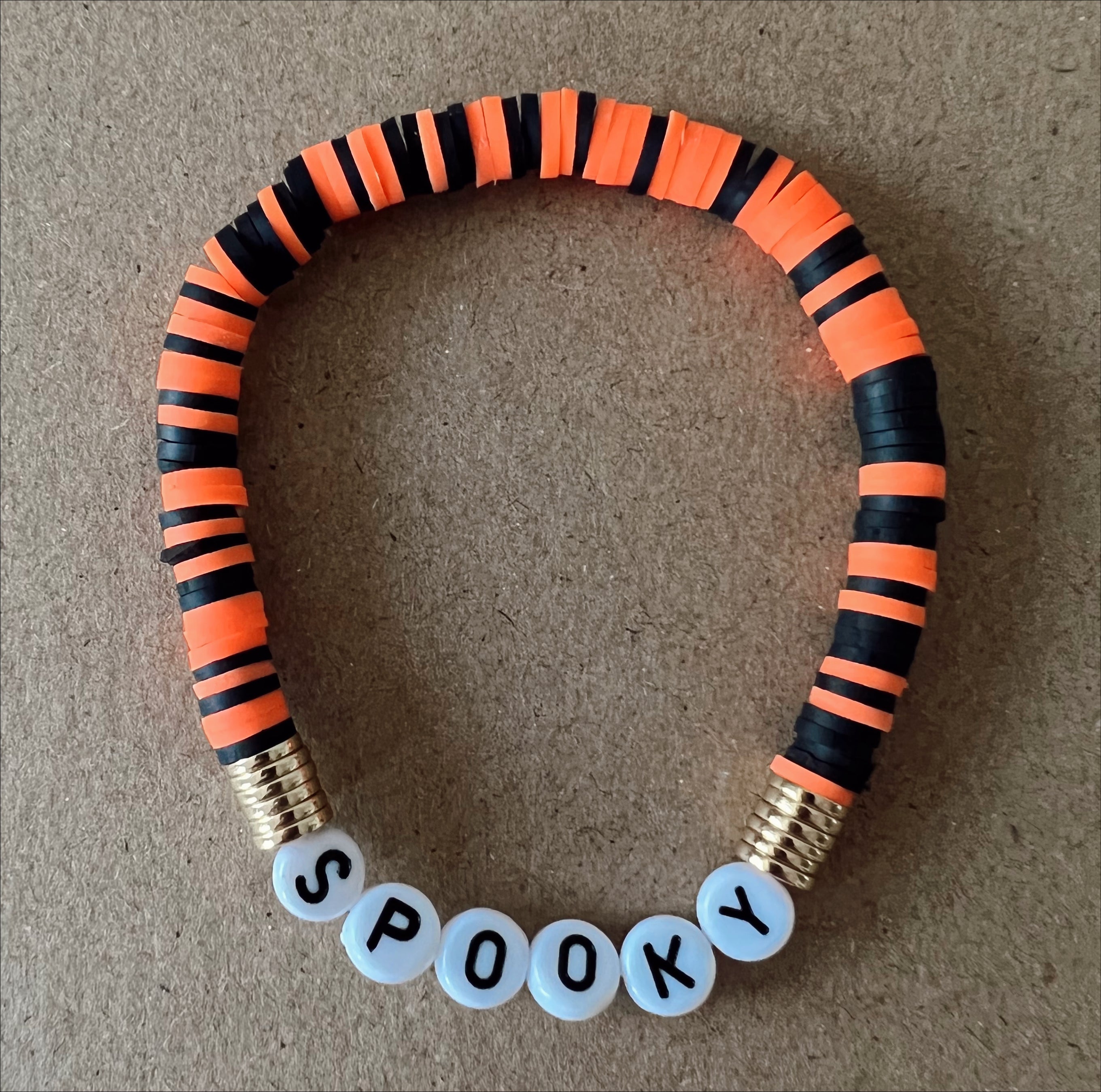 Halloween-themed bracelet with black and orange bands, featuring the word "SPOOKY" in white beads.