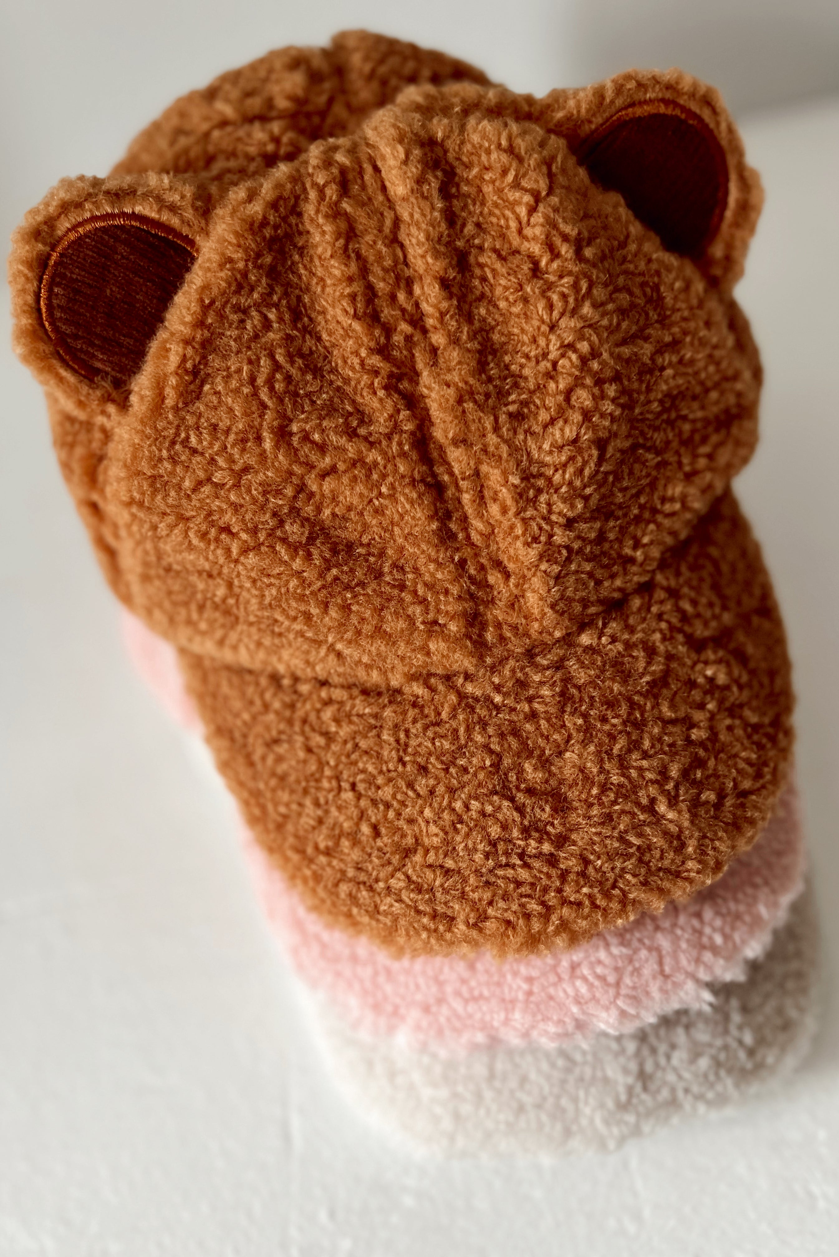 Brown fuzzy beanie with bear ears and a gradient of pink shades on the brim. Ideal for warmth and style.