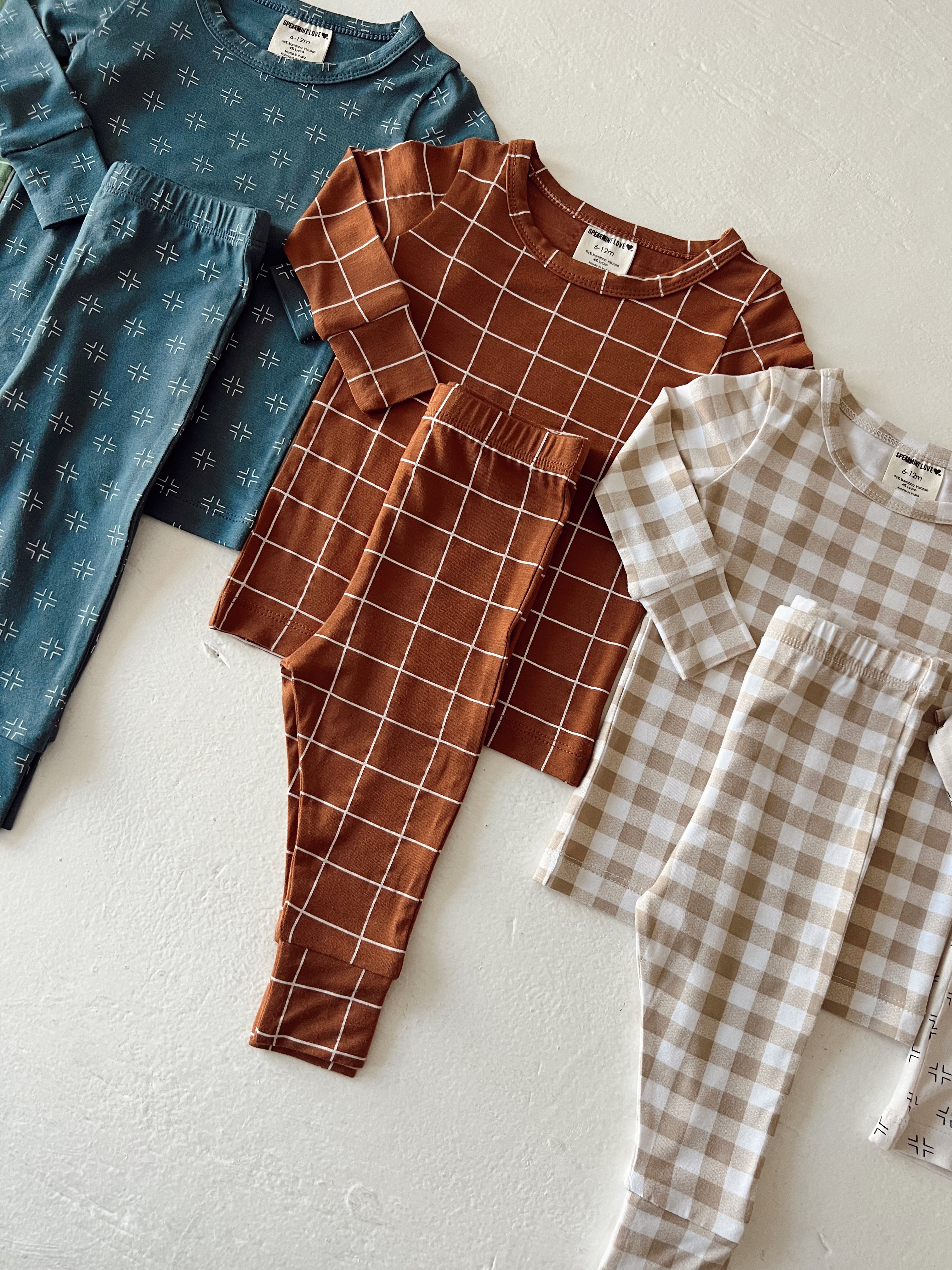 Three sets of children's outfits: teal, brown checkered, and beige plaid, displayed on a light background.