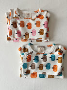 Two folded toddler shirts featuring colorful pumpkin patterns on a white background.