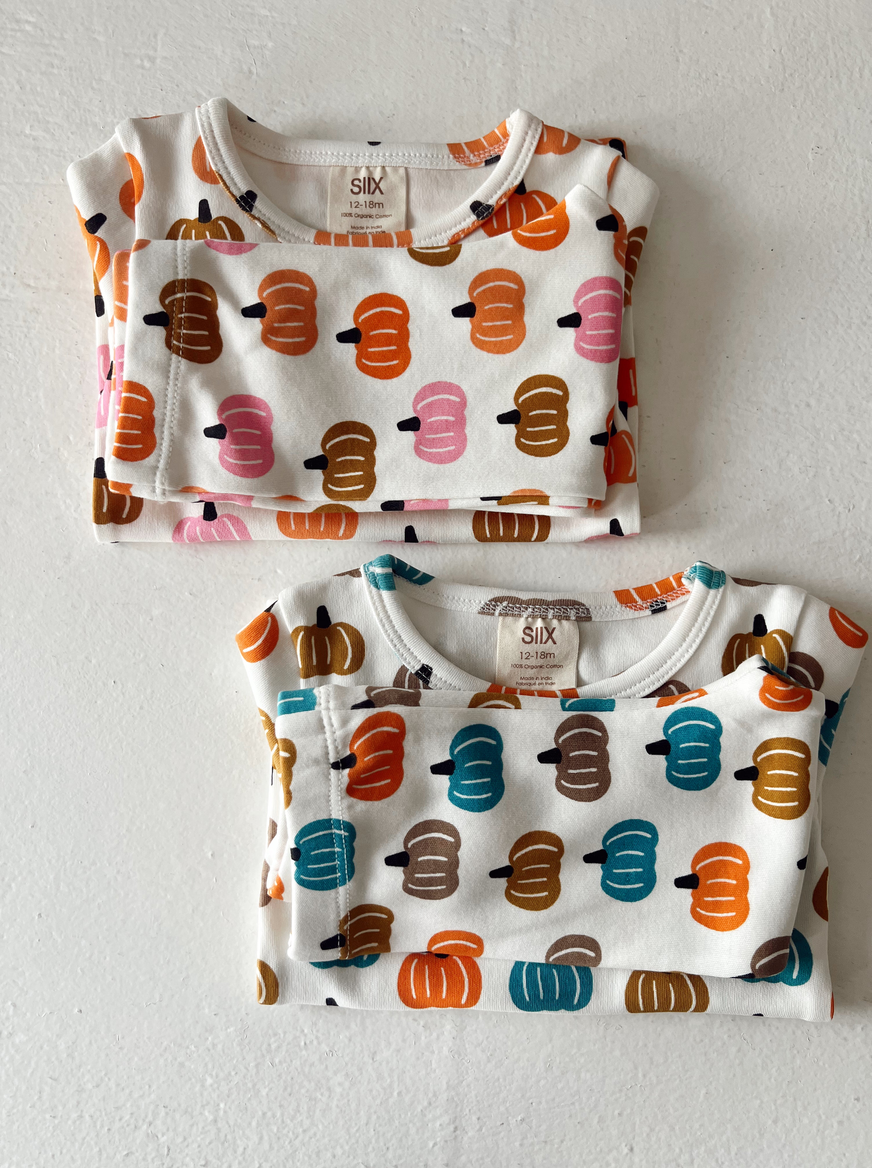 Two folded toddler shirts featuring colorful pumpkin patterns on a white background, sizes 12-18 months.