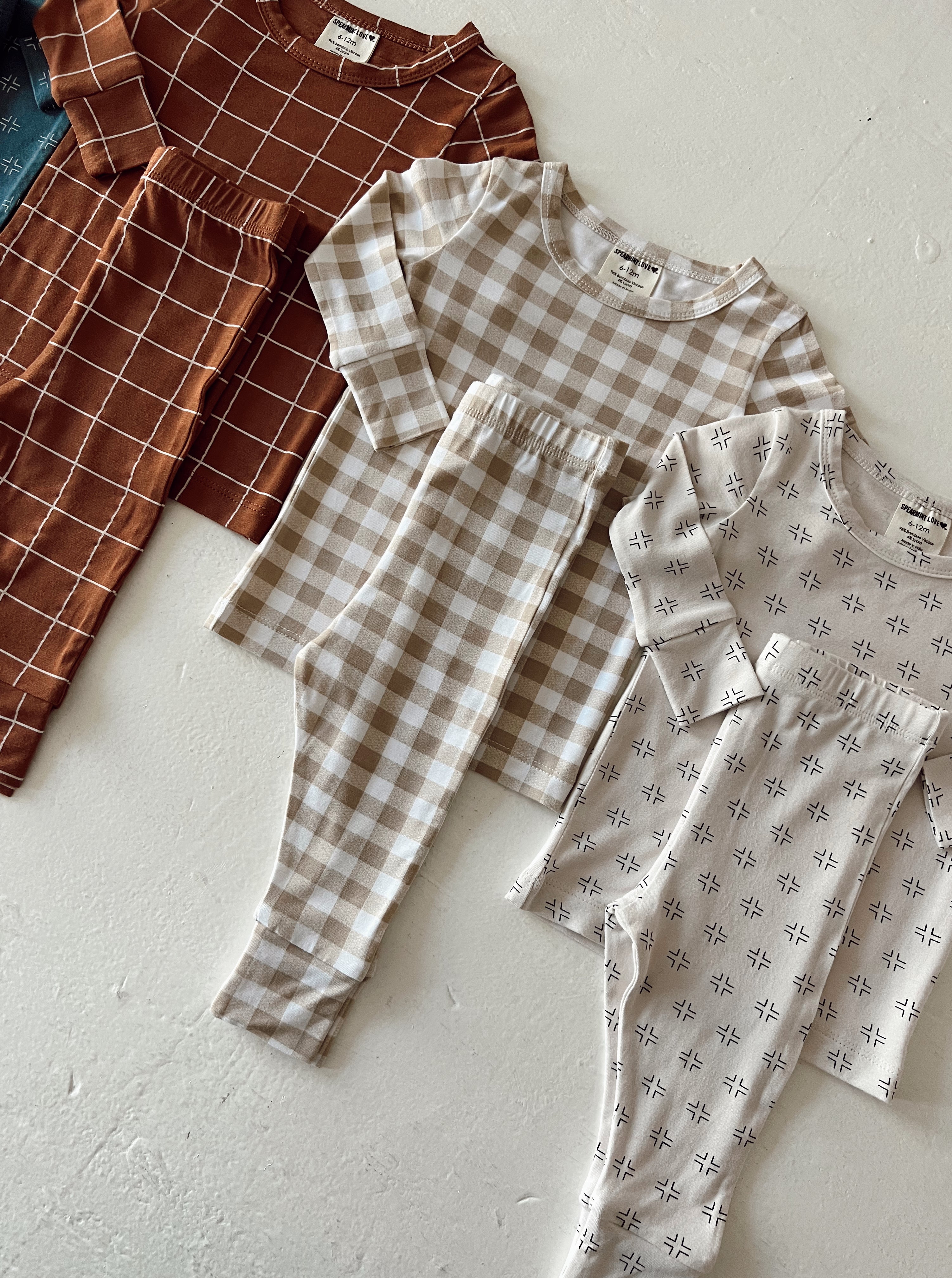 Set of children's pajamas featuring various patterns: checkered, grid, and abstract designs in earthy tones.