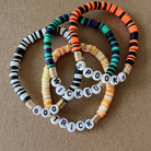Colorful beaded bracelets with words "Spooky," "Wicked," and "Boo Trick," on a textured background.