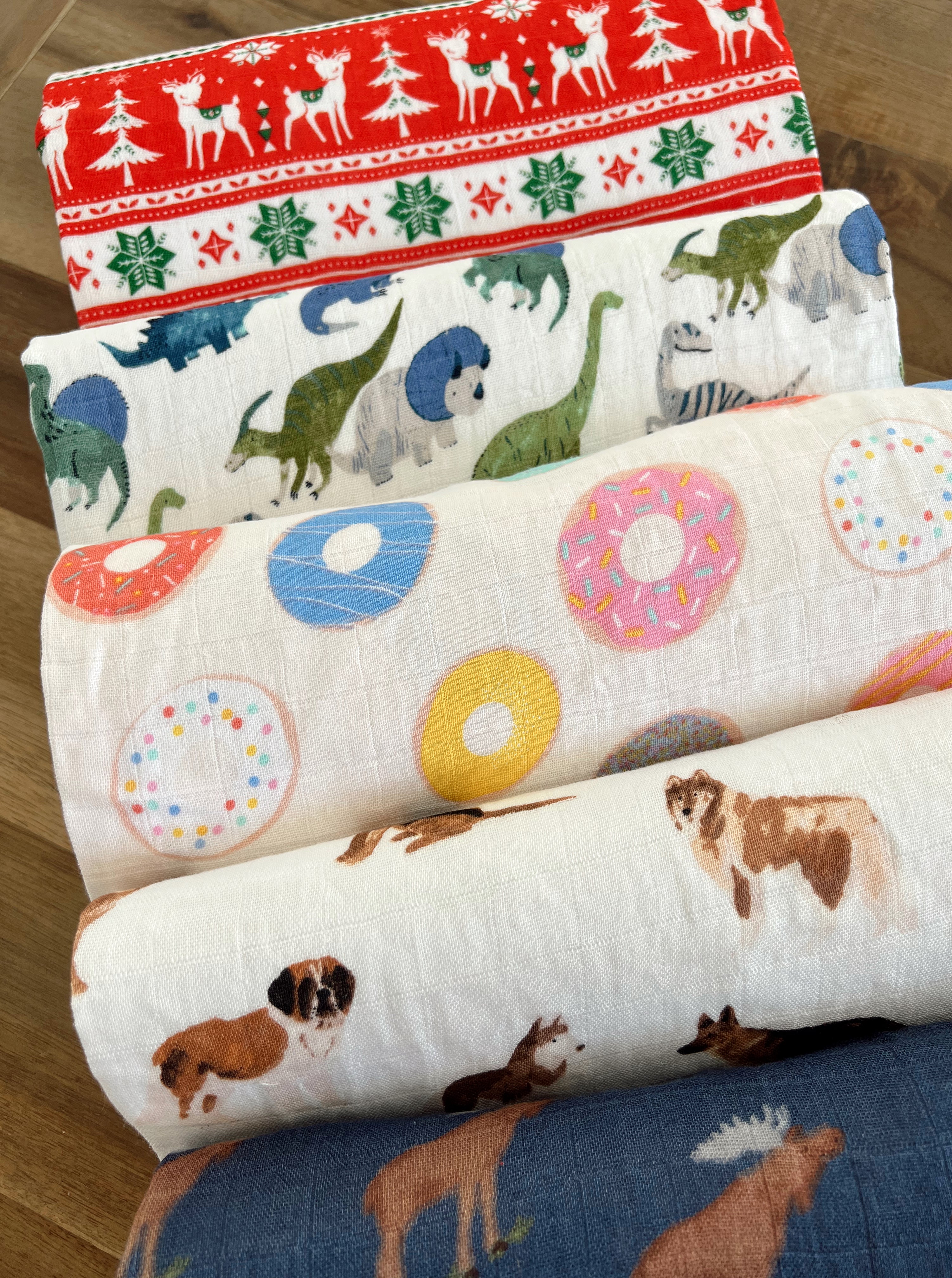 Five patterned fabric rolls featuring animals, donuts, dinosaurs, and festive designs in vibrant colors.