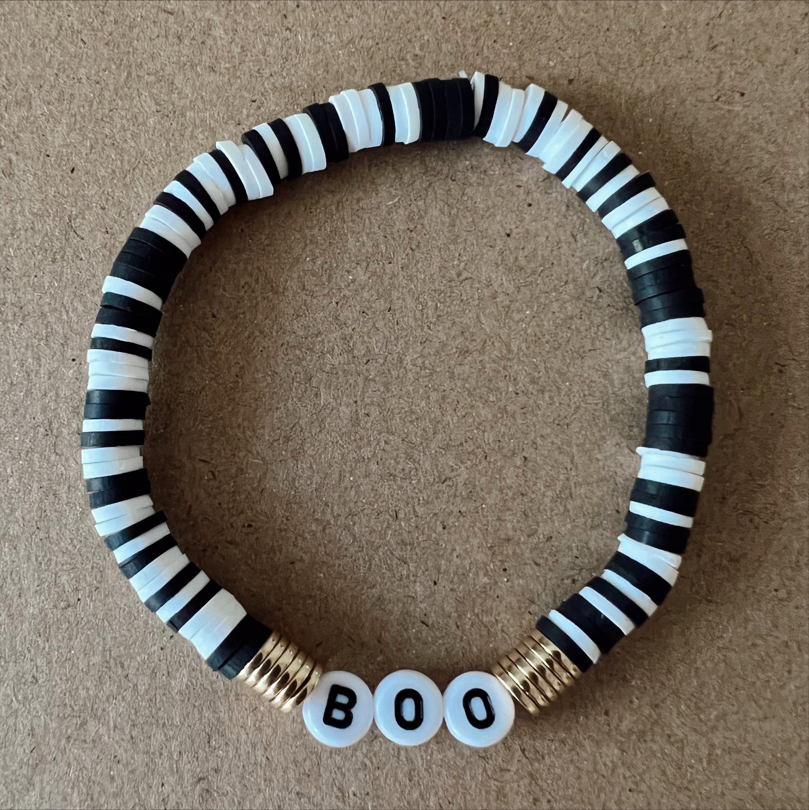 Black and white beaded bracelet with gold spacers and the word "BOO" in white beads.