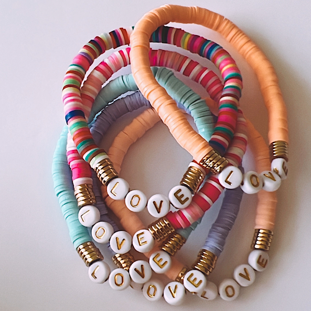Colorful beaded bracelets featuring the word "LOVE" on white beads, layered together.