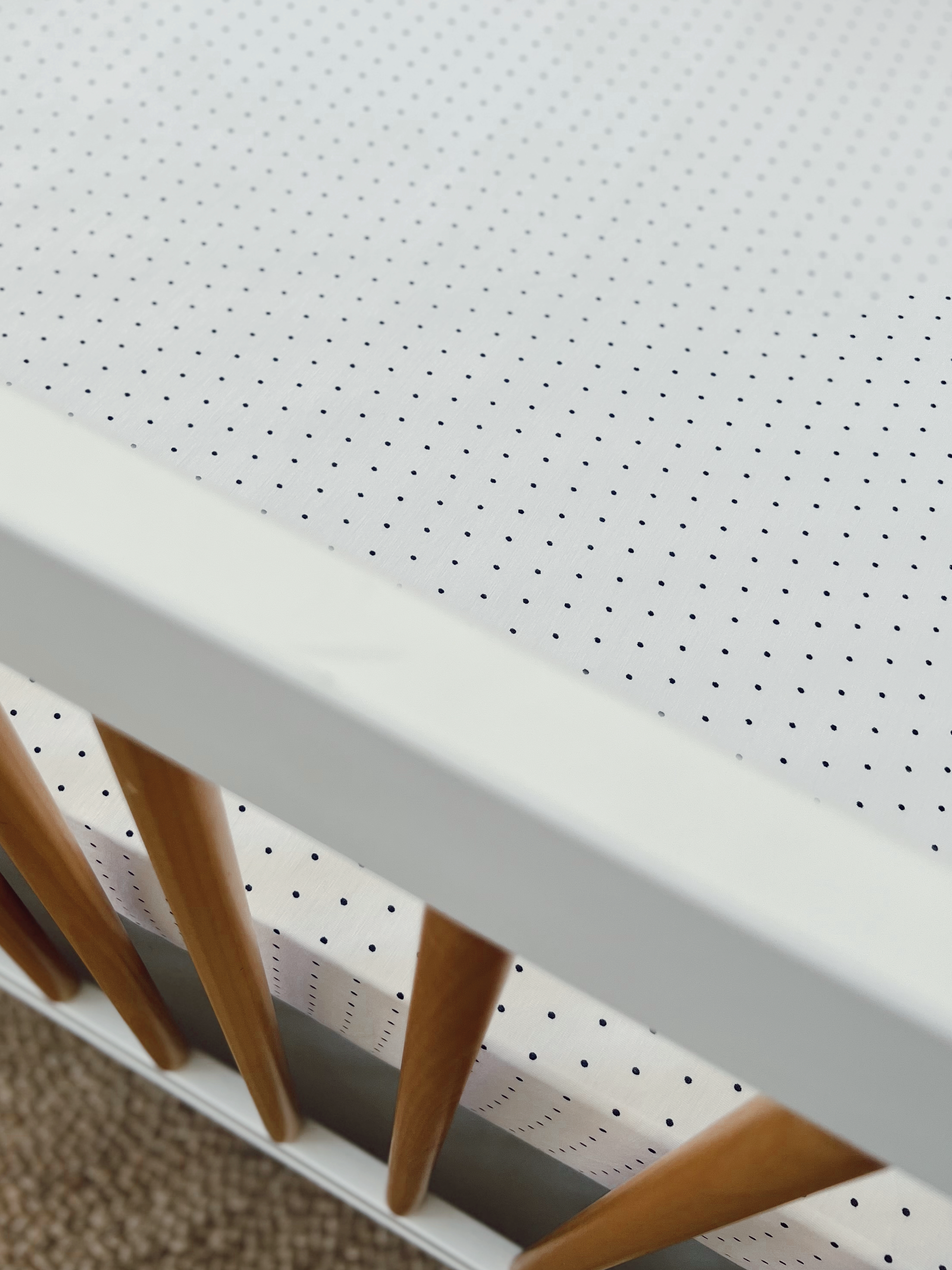 Top view of a white crib featuring a dotted bedding pattern and wooden slats.