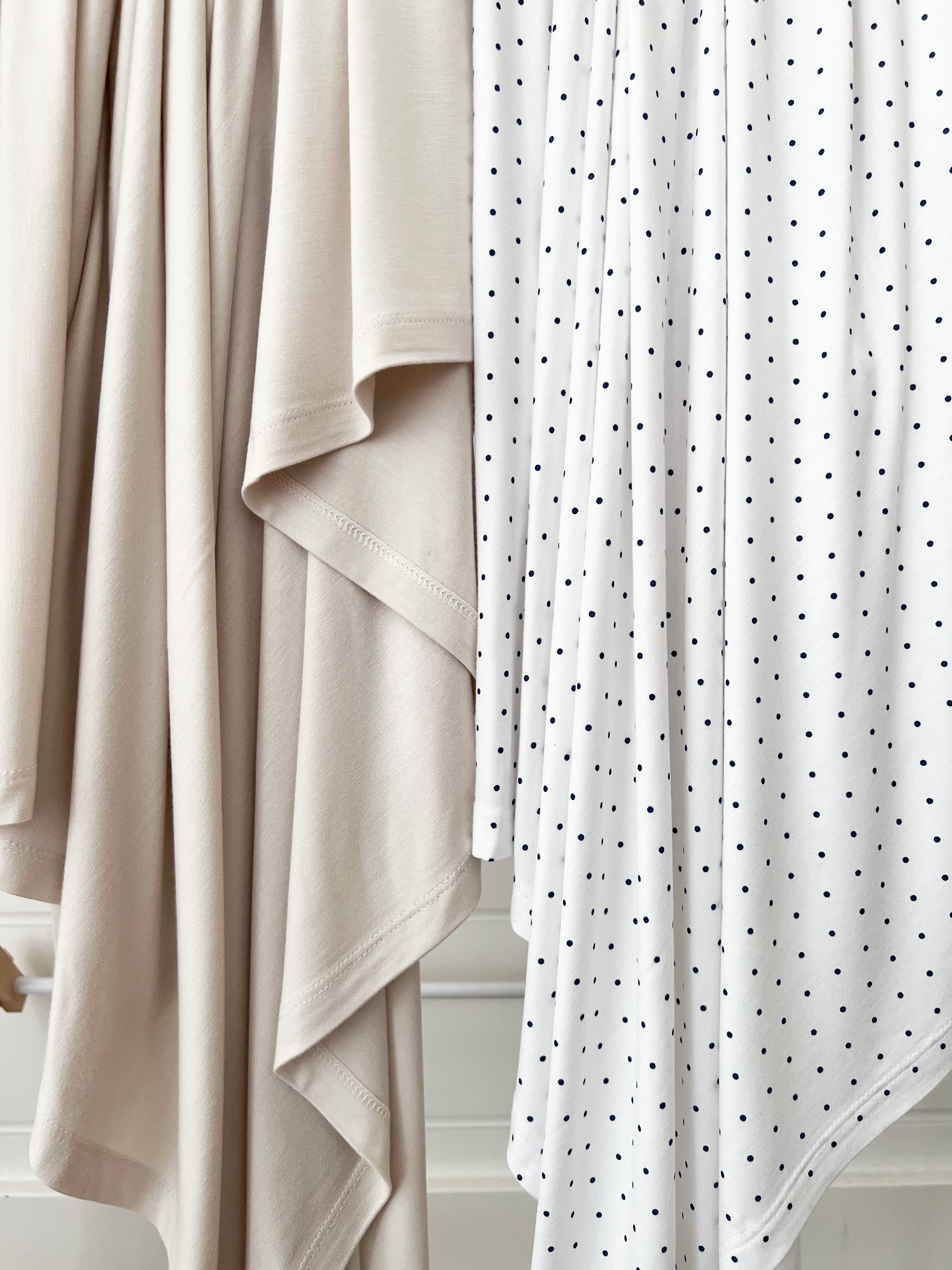 Two pieces of fabric: a beige draped textile and a white fabric with navy polka dots, hanging next to each other.