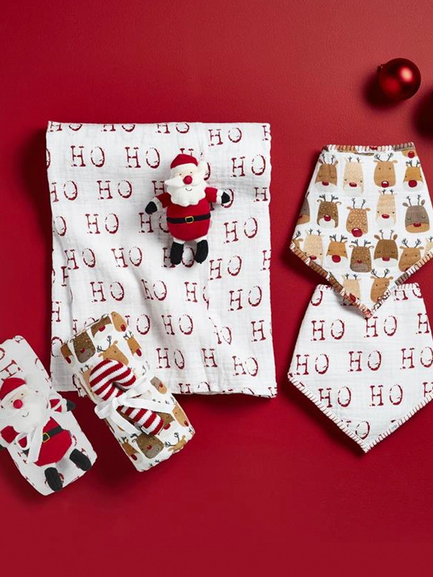Holiday-themed napkins, featuring Santa and reindeer designs, on a red background with festive ornaments.
