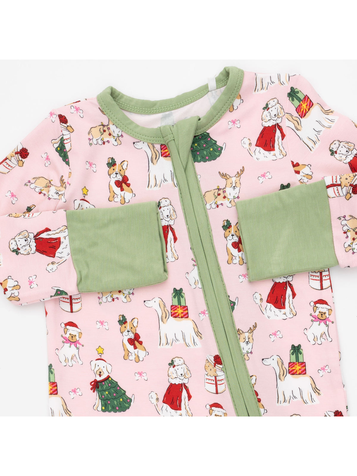 Pink pajama onesie featuring festive dogs, Christmas gifts, and holiday decorations with green cuffs.