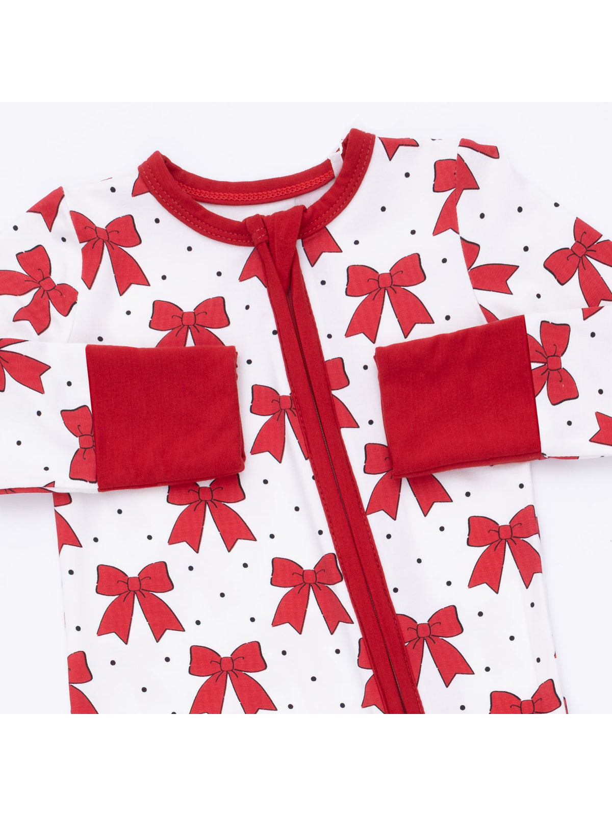 Red and white baby onesie with bow patterns and polka dots, featuring a front zipper and pockets.