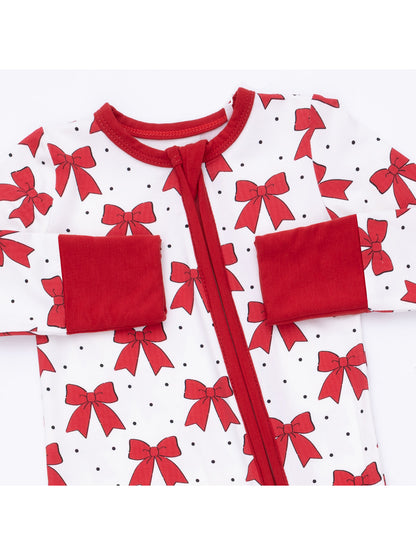 Red and white baby onesie with bow patterns and polka dots, featuring a front zipper and pockets.