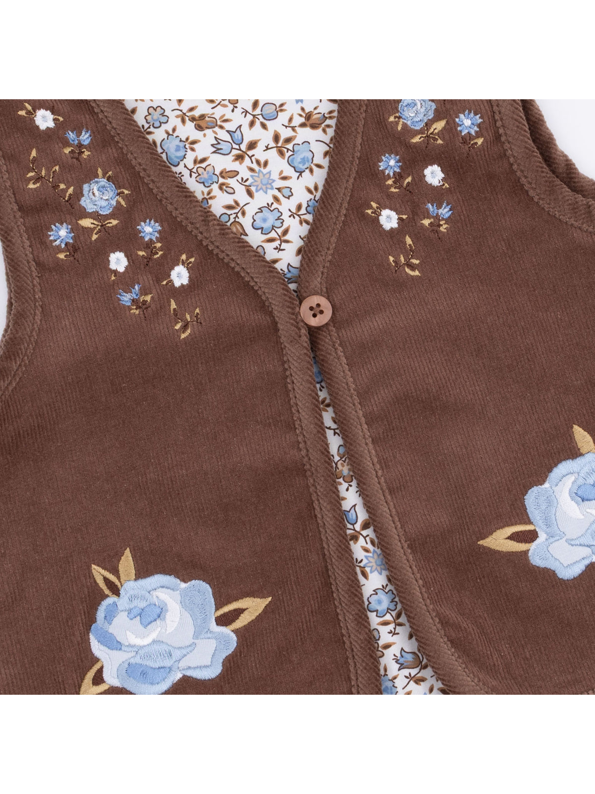 Brown vest with blue floral embroidery and button closure, layered over a floral patterned shirt.