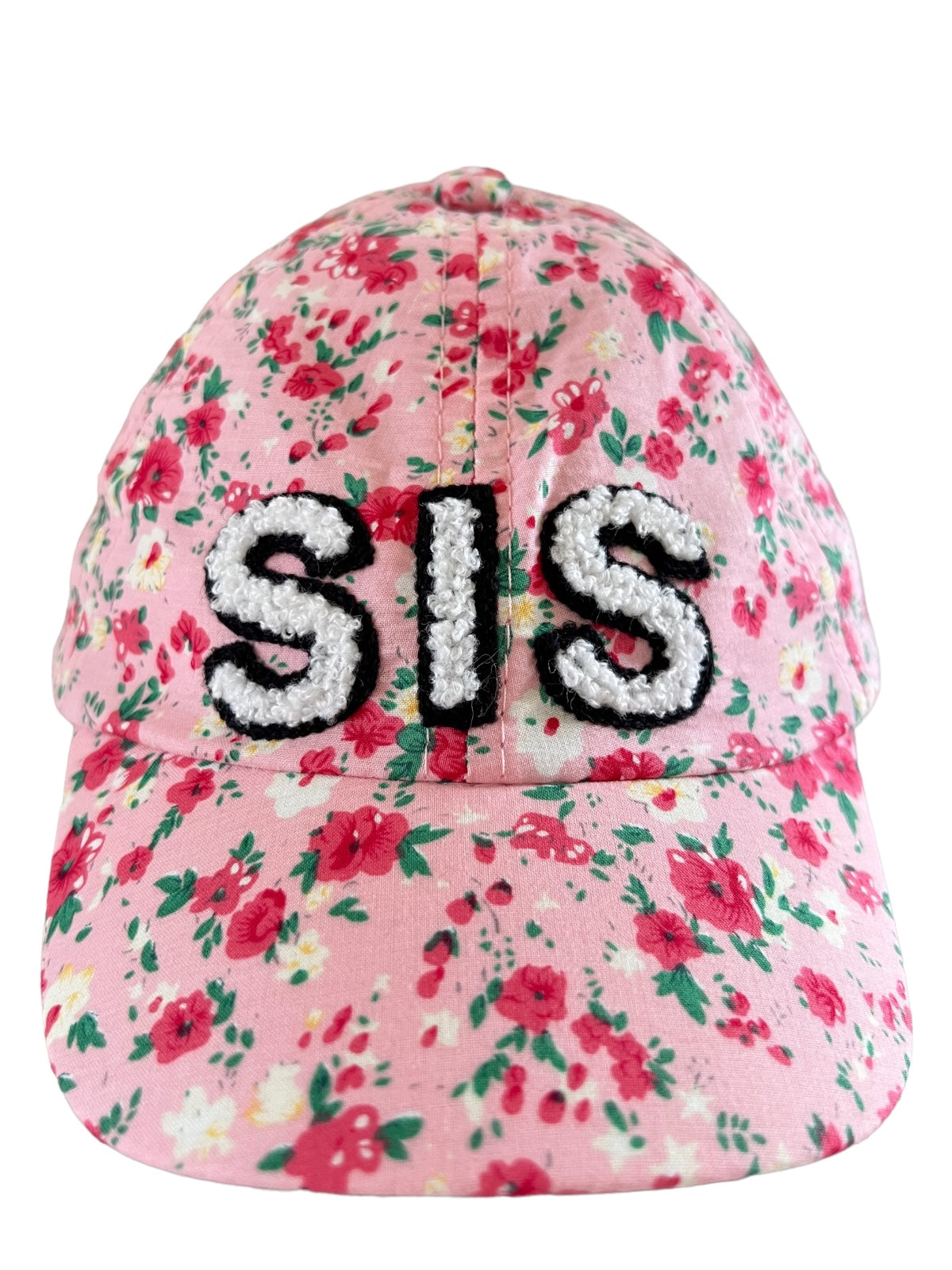 Floral pink baseball cap featuring the word "SIS" in contrasting textured letters.