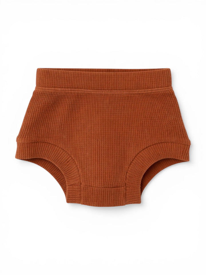 Rust-colored ribbed toddler underwear on a white background.
