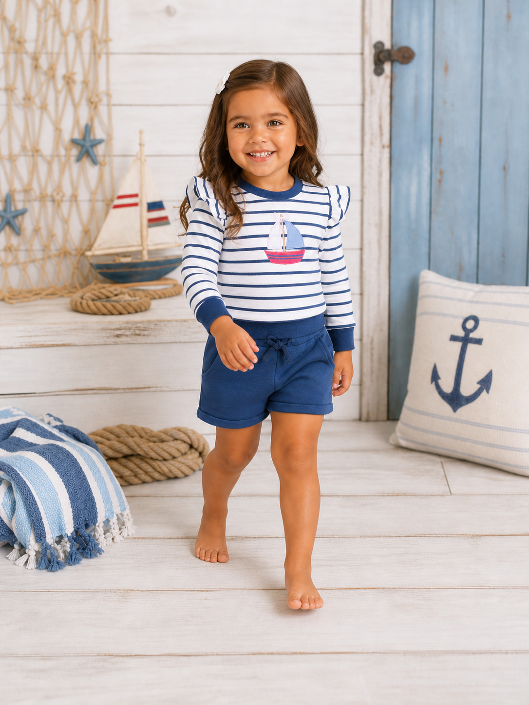 Smiling girl in striped shirt and shorts walking in a nautical-themed room with decorative elements.