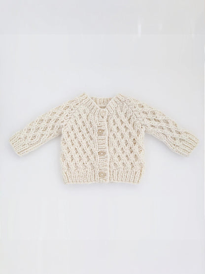 Cream-colored knitted baby cardigan with intricate patterns and three buttons at the front.