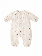 Cream-colored baby romper with brown polka dots and button closure, featuring long sleeves and snap bottom.