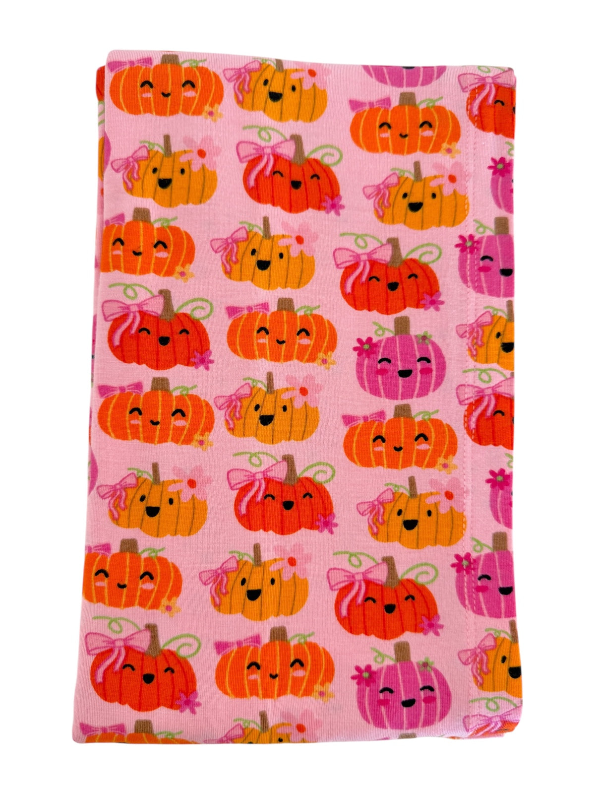 Pink fabric covered with cute, smiling pumpkins in various colors and designs. Perfect for fall-themed projects.