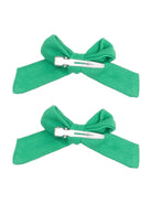 Two green fabric hair bows with metal clips arranged symmetrically.