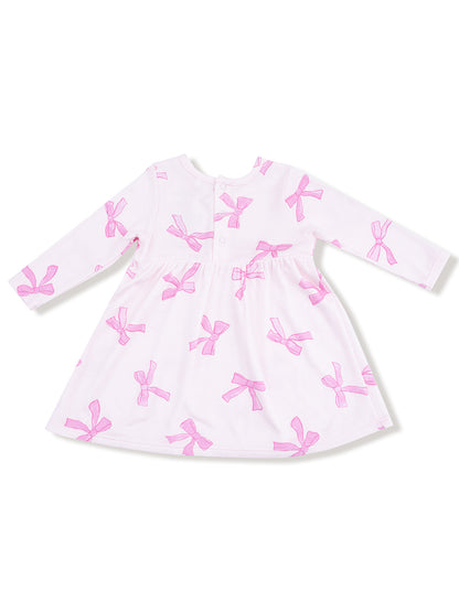 White dress with pink bow patterns and long sleeves, featuring a back button closure.