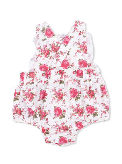 White floral romper with pink roses and green leaves, featuring cross-back straps and ruffled detailing.