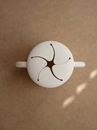 Top view of a white modern mug with a star-shaped cutout design on the lid against a beige background.