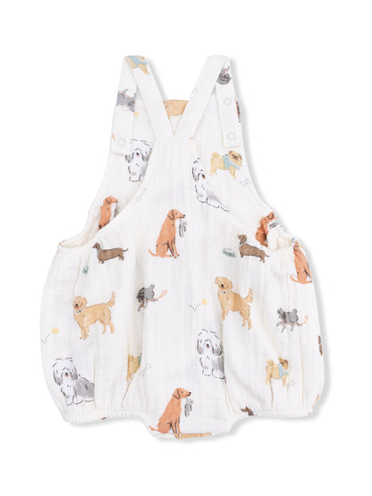 White baby romper with colorful dog prints, featuring straps and gathered waist. Ideal for playful, casual outfits.