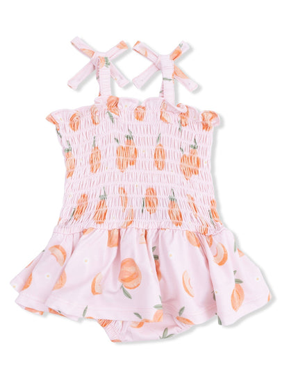 Pink infant romper with peach print, smocked bodice, and crisscross straps. Perfect for summer outings.