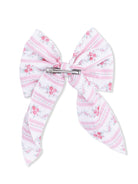 Pink floral bow with stripes, secured by a silver clip, on a plain white background.