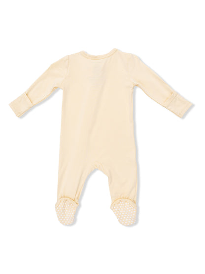 Cream-colored baby onesie with long sleeves and polka dot grips on feet, viewed from the back.
