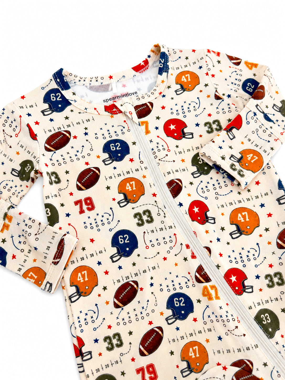 Football-themed baby onesie with colorful helmets, footballs, and stars on a cream background.